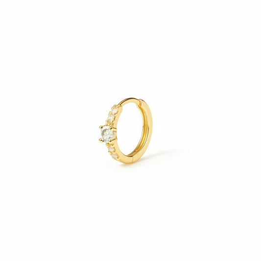 Gold hoop earring with a central gemstone on a white background